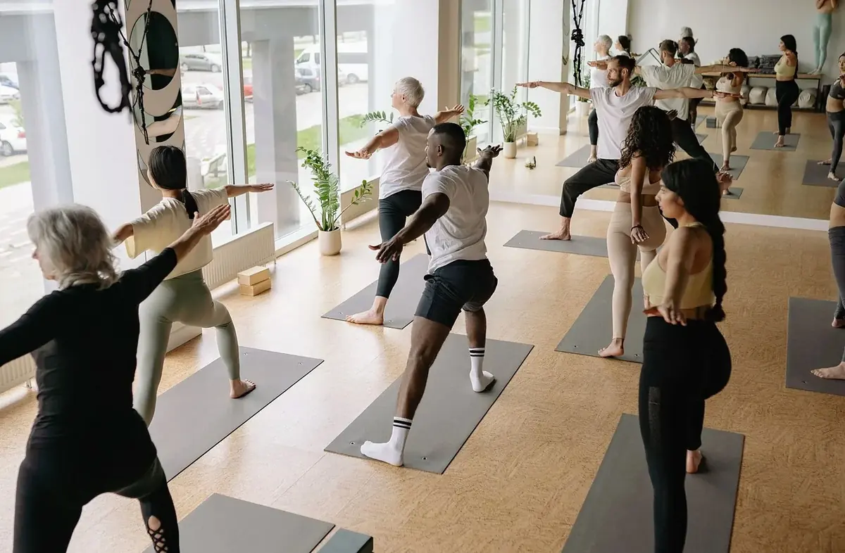 Group class in a bright studio, students in a standing pose on mats